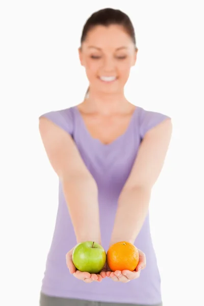 Mulher atraente segurando frutas enquanto está de pé — Fotografia de Stock