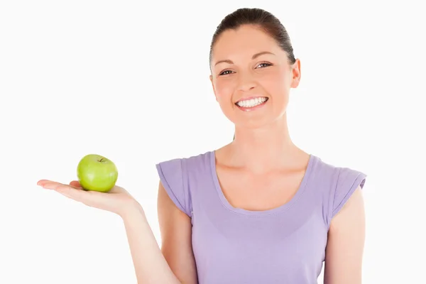 Beautiful woman holding an apple while standing — Stock Photo, Image