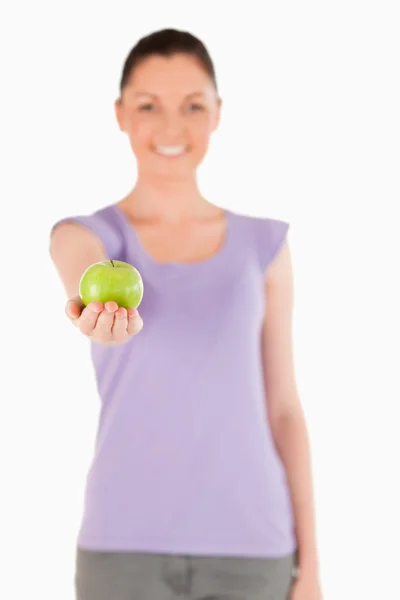 Lovely woman holding an apple while standing — Stock Photo, Image