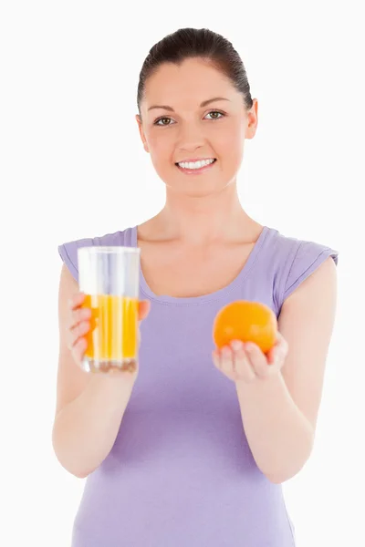 Retrato de una mujer atractiva sosteniendo una naranja y un vaso de — Foto de Stock