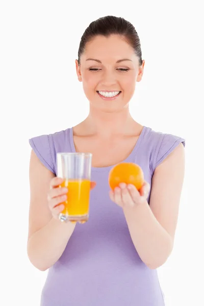 Retrato de uma mulher atraente segurando uma laranja e um copo de — Fotografia de Stock