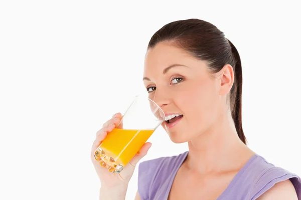 喝了一杯橙汁站立时有吸引力的女人 — 图库照片