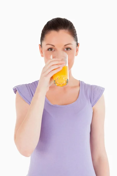 Ładna kobieta wypija szklankę soku pomarańczowego, stojąc — Zdjęcie stockowe