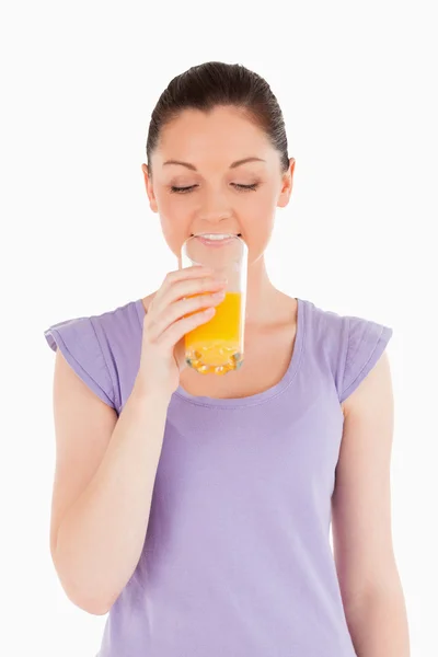 Γοητευτική γυναίκα πίνοντας ένα ποτήρι χυμό πορτοκαλιού, ενώ στέκεται — Φωτογραφία Αρχείου