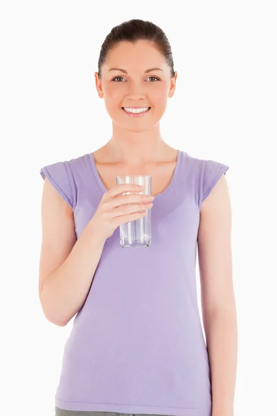 Affascinante donna in possesso di un bicchiere d'acqua mentre in piedi — Foto Stock