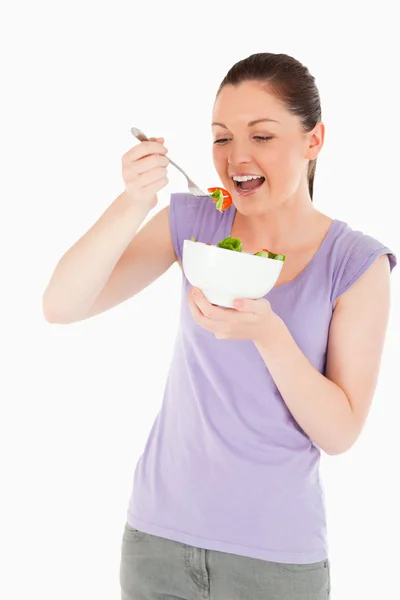 Красива жінка їсть тарілку салату, стоячи — стокове фото