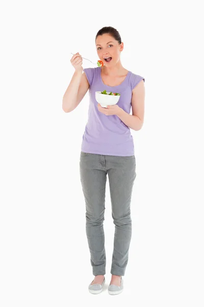 Πανέμορφη γυναίκα που τρώει ένα μπολ της σαλάτας ενώ στέκεται — Φωτογραφία Αρχείου