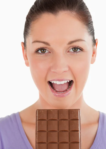 Retrato de una mujer atractiva comiendo un bloque de chocolate mientras s — Foto de Stock