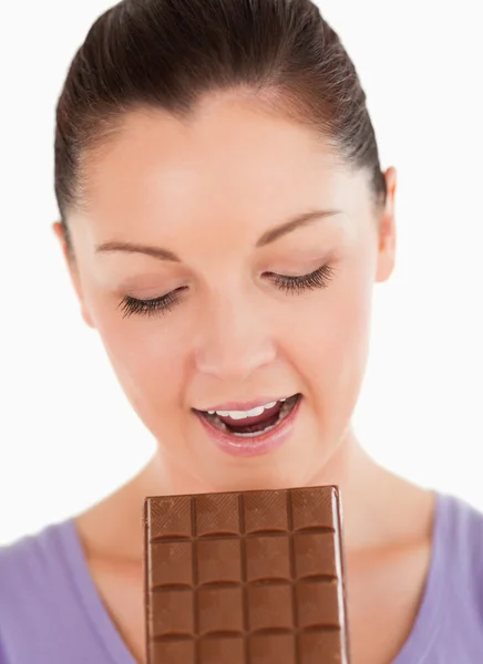 Porträt einer hinreißenden Frau, die einen Schokoladenblock isst, während sie — Stockfoto