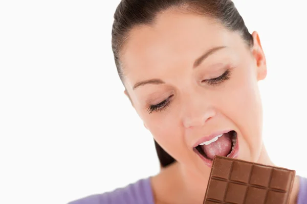 Retrato de uma mulher encantadora comendo um bloco de chocolate, enquanto stan — Fotografia de Stock