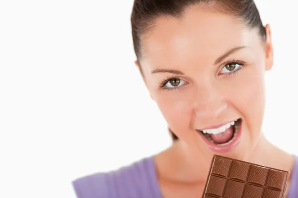 Porträt einer hübschen Frau, die im Standby einen Schokoladenblock isst — Stockfoto