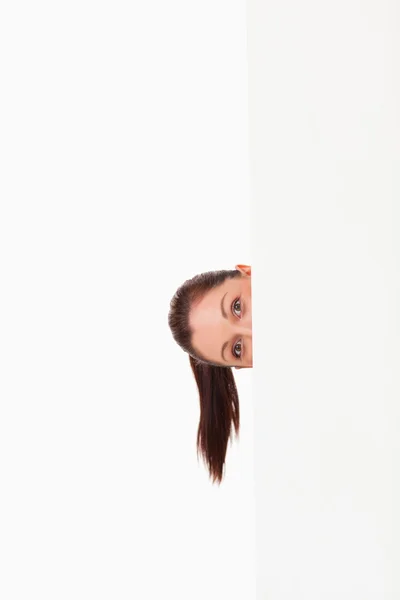 Lovely woman hiding behind a billboard while standing — Stock Photo, Image