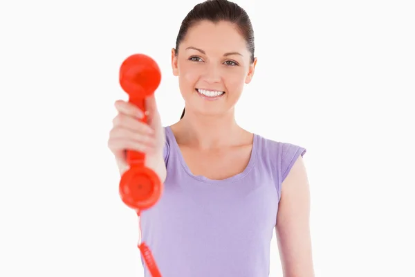 Good looking woman holding a red telephone while standing — Stock Photo, Image