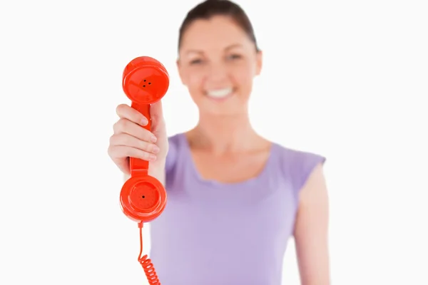 Krásná žena drží červený telefon, stoje — Stock fotografie