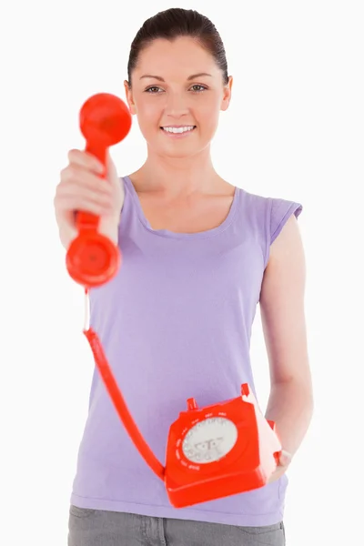 Okouzlující žena drží červený telefon, stoje — Stock fotografie