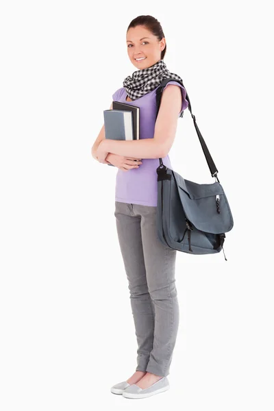 Estudante atraente segurando livros e sua bolsa enquanto está de pé — Fotografia de Stock