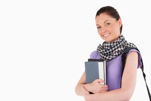 Хорошо выглядящая студентка держит книги и сумку, стоя — стоковое фото