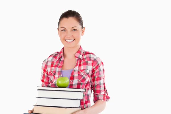 Beautiful female holding and a apple and books while posing — Stock Photo, Image