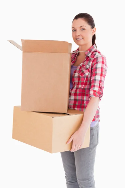 Mujer atractiva sosteniendo cajas de cartón mientras está de pie —  Fotos de Stock