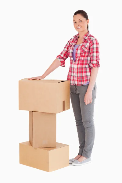 Beautiful woman posing with cardboard boxes while standing — Stock Photo, Image