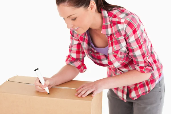 Portrait of a beautiful woman writing on cardboard boxes with a — Stock Photo, Image