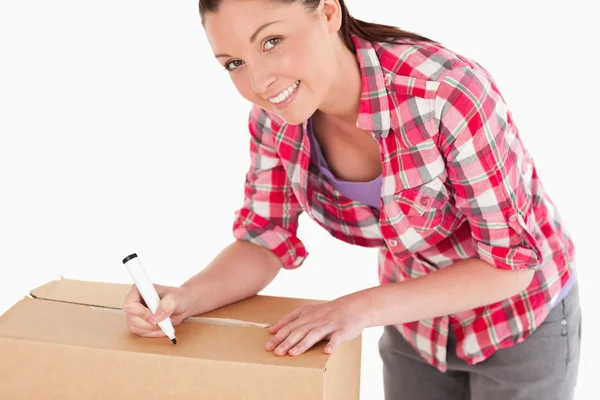 Portrait of an attractive woman writing on cardboard boxes with — Stock Photo, Image