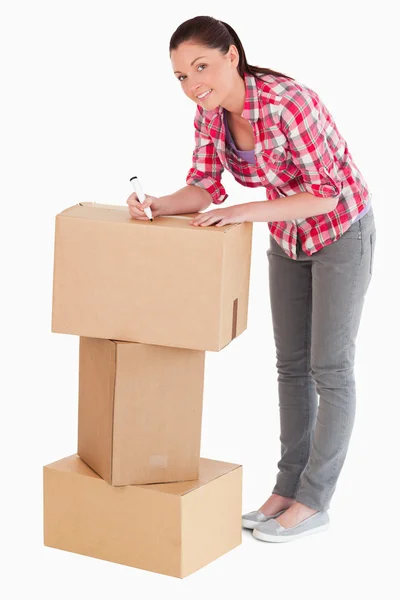 Karton kutular ile bir işaretleyici ızg yazma iyi görünümlü kadın — Stok fotoğraf