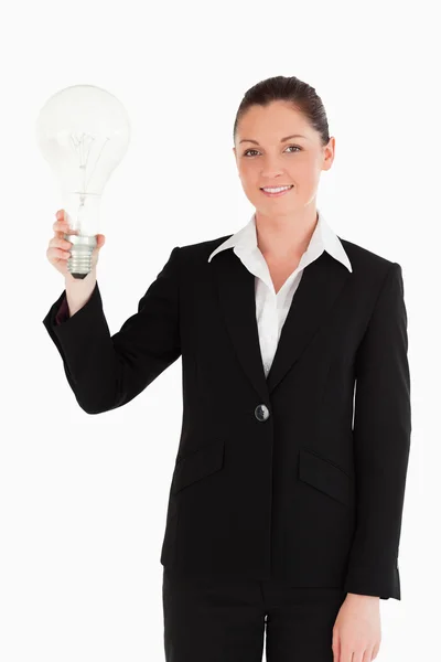 Linda mulher de terno segurando uma lâmpada enquanto está de pé — Fotografia de Stock