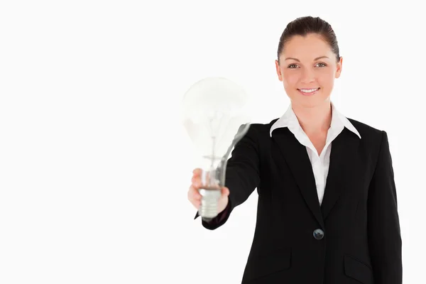 Atraktivní žena v obleku drží žárovku stoje — Stock fotografie