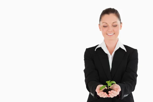 Vacker kvinna i kostym som håller en liten växt — Stockfoto