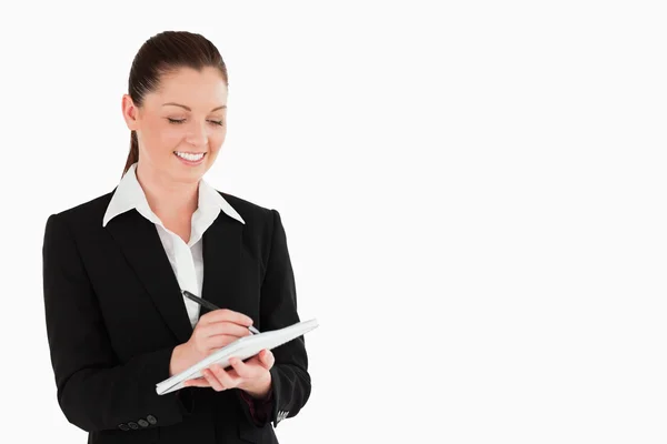 Portrait of a charming woman in suit writing on a notebook — Stock Photo, Image