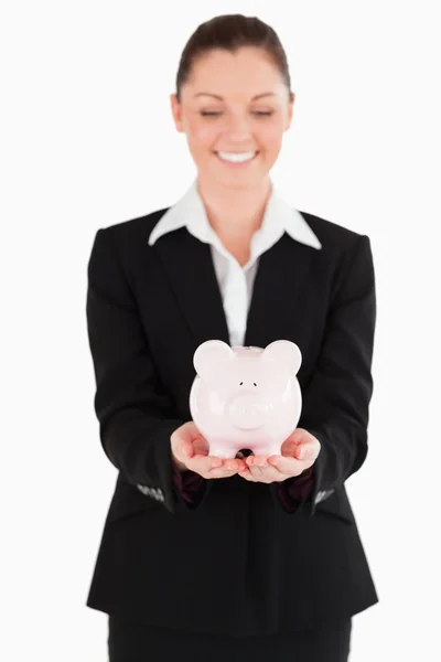 Jó kinézetű nő öltöny kezében egy rózsaszín malacka bank — Stock Fotó