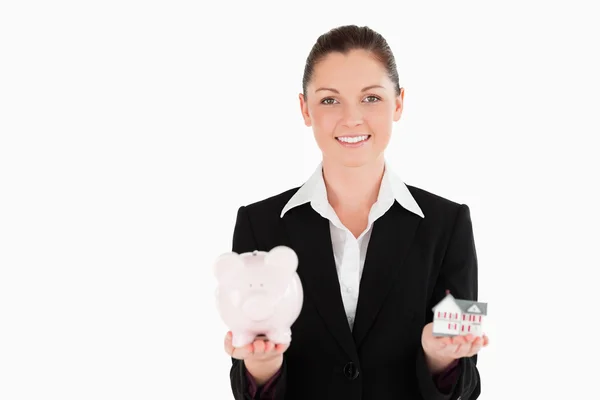 Mooie vrouw in pak holding een piggy bank en een miniatuur hou — Stockfoto