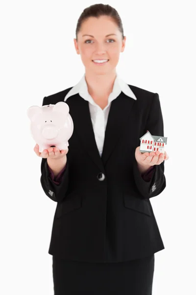 Mulher bonita em terno segurando um banco porquinho e uma miniatura — Fotografia de Stock
