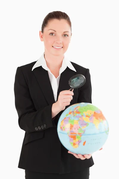 Charmante vrouw in pak een globe bedrijf en met behulp van een vergrootglas g — Stockfoto