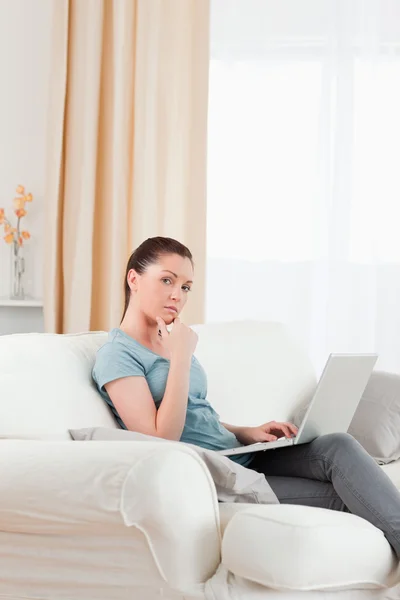Mujer triste relajarse con su ordenador portátil mientras está sentado en un sofá — Foto de Stock
