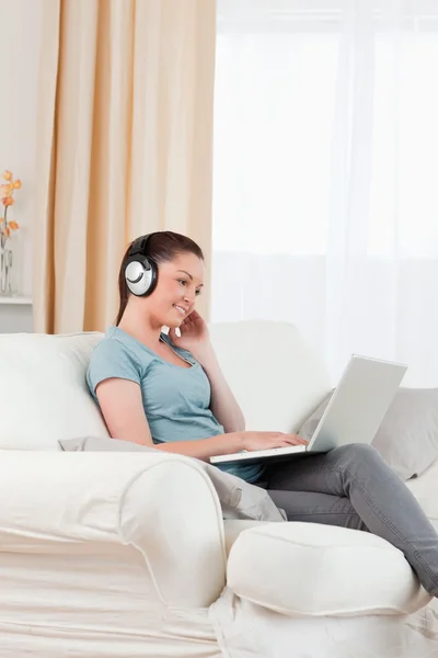Красива жінка з навушниками розслабляється зі своїм ноутбуком в той час як s — стокове фото