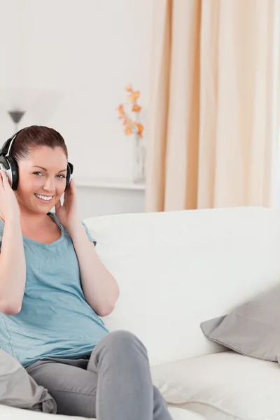 Mulher bonita relaxante com fones de ouvido enquanto sentado em um s — Fotografia de Stock