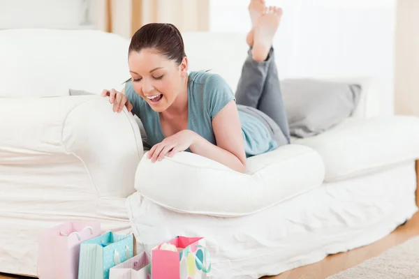Beautiful woman looking at her shopping bags while lying on a so — Stock Photo, Image