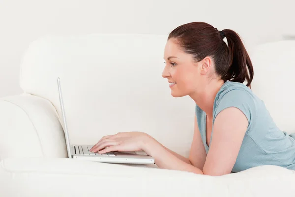 Zijaanzicht van een mooie vrouw ontspannen met haar laptop terwijl ly — Stockfoto