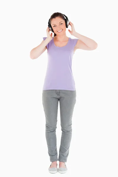 Mujer atractiva posando con auriculares mientras está de pie —  Fotos de Stock