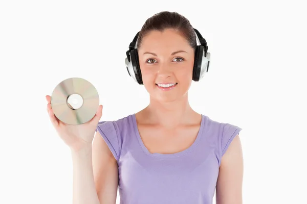 Good looking woman with headphones holding a CD while standing — Stock Photo, Image