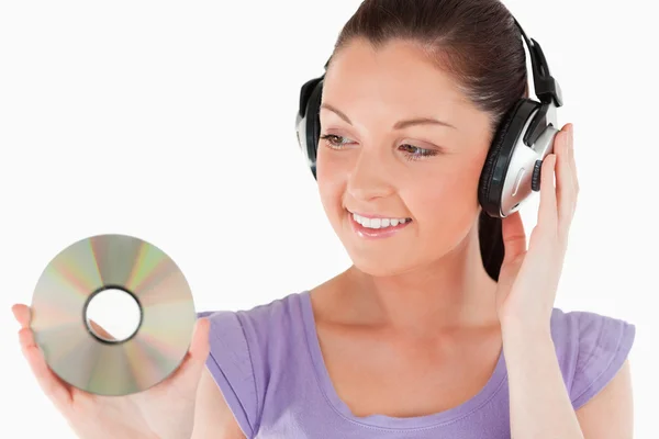 Beautiful woman with headphones holding a CD while standing — Stock Photo, Image