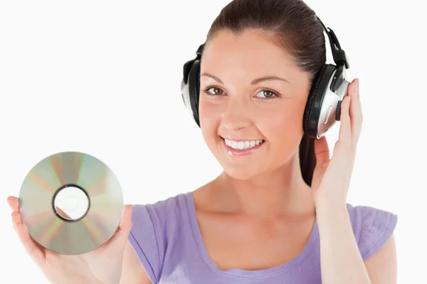 Attractive woman with headphones holding a CD while standing — Stock Photo, Image