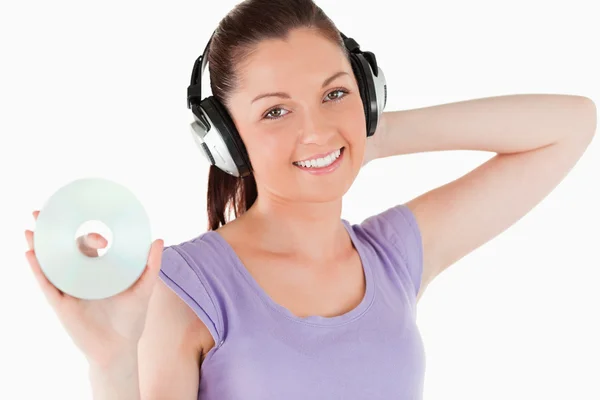 Charmante Frau mit Kopfhörern, die im Stehen eine CD hält — Stockfoto