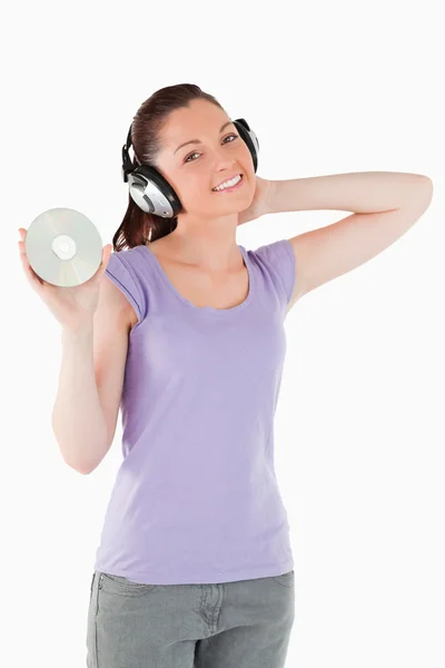 Hübsche Frau mit Kopfhörern, die im Stehen eine CD hält — Stockfoto
