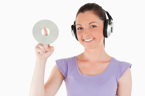 Härlig kvinna med hörlurar håller en cd när du står — Stockfoto