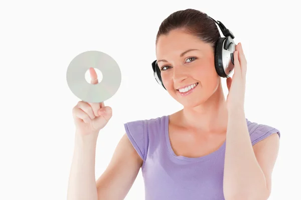 Cute woman with headphones holding a CD while standing — Stock Photo, Image