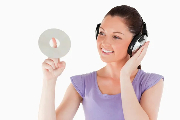 Dobra kobieta szuka ze słuchawkami gospodarstwa cd stojąc — Zdjęcie stockowe