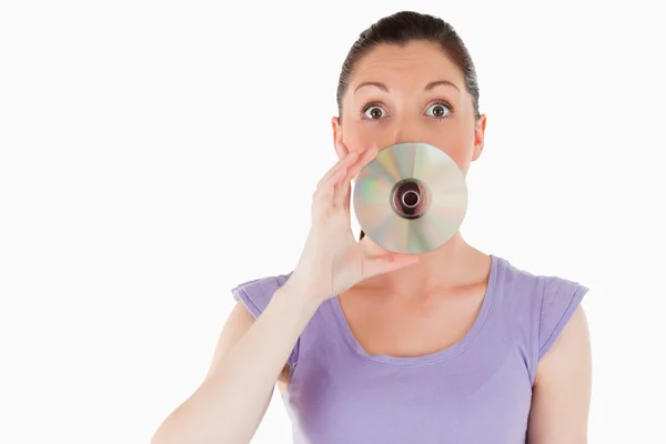 Belle femme cachant sa bouche avec un CD — Photo
